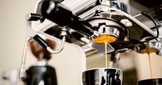 an espresso machine pouring coffee into two cups