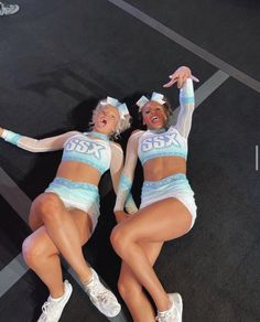 two cheerleaders are laying on the ground