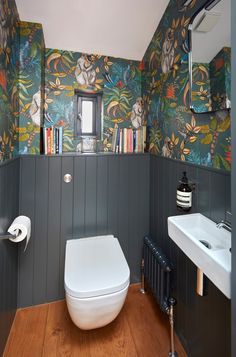 a toilet and sink in a small room with wallpaper on the walls behind it