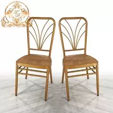 two wooden chairs sitting side by side in front of a white wall with an ornamental design on the back