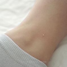 a small star tattoo on the side of a woman's ankle, with tiny stars