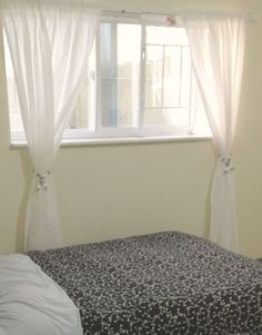 a bed with a black and white bedspread in front of a large window