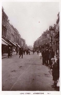 an old black and white photo of people walking down the street