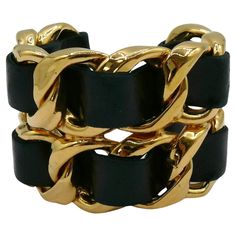 CHANEL by KARL LAGERFELD vintage iconic gold toned rigid chain cuff bracelet featuring woven black leather. Collection year n°23 (1988). VICTOIRE DE CASTELLANE era. Embossed CHANEL 2 3 Made in France. Indicative measurements : inner circumference approx. 18.85 cm (7.42 inches) / width approx. 5.5 cm (2.17 inches) / wrist opening approx. 3 cm (1.18 inches). Materials : Gold tone metal hardware / Leather. NOTES - This is a preloved vintage item, therefore it might have imperfections. - Colors may Gold Leather Cuff Bracelet For Formal Occasions, Gold Leather Cuff Bracelet, Formal Gold Leather Cuff Bracelet, Vintage Gold Leather Bracelet, Gold Vintage Leather Bracelet, Gold Leather Cuff Jewelry, Luxury Vintage Link Chain Bracelet, Luxury Vintage Metal Bracelet, Chanel Bangle