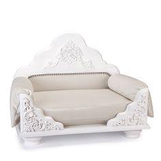 a white chair with ornate carvings on the armrests and foot rest, sitting in front of a white background