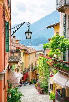 a person walking down an alley way with umbrellas on the side and mountains in the background