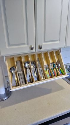 an organized kitchen drawer with utensils and spoons in the bottom compartment, on a countertop