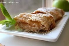 a pastry on a white plate with some green leaves and limes in the background