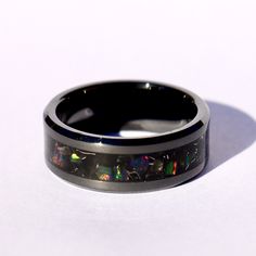 The Eclipse Ring, Handmade Black Ceramic Custom Ring, Black Fire Opal Meteorite Obsidian Inlay Ring, Glow in the Dark Ring for Men & Women This is the Eclipse Ring, made with Black Fire Opal, Obsidian, and Meteorite shavings on a black background and glows blue. The primary color of the Black Fire Opal is Black with constantly shifting colors like hints of purple, red, green, blue and yellow. The Meteorite shavings add contrast to the ring, highlighting the opal as well as the black ceramic Black Inlay Jewelry As A Gift, Black Jewelry With Inlay For Gift, Black Ring With Inlay, Black Rings With Inlay, Black Inlay Round Ring, Formal Black Opal Ring, Black Opal Gemstone Ring, Eclipse Ring, Glow In The Dark Ring