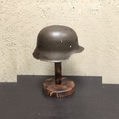 a metal helmet sitting on top of a wooden stand