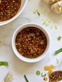 two white bowls filled with chili and green beans on top of a marble countertop