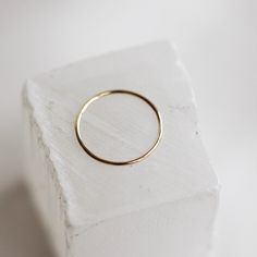 The Bare Gold Stacker is a smooth, solid gold 1mm band and a true go-to for any stack. This skinny ring is so versatile, giving a subtle option that stands alone, while also effortlessly adding a splash of golden shine to your stack. The Bare Gold Stacker is our #1 bestselling ring, both online and in-store, and is a classic piece that will make you feel golden. We are positive you'll never want to take this one off! Simple Everyday Jewelry With Smooth Bezel, Minimalist 14k Gold Stackable Midi Rings, Minimalist Gold Stackable Bands, Minimalist Stackable Gold Bands, Minimalist Yellow Gold Band As Gift, Simple 14k Gold Stackable Rings Tarnish Resistant, Stackable Yellow Gold Midi Rings For Everyday, Yellow Gold Stackable Midi Rings For Everyday, Minimalist Stackable Rings With Smooth Bezel