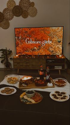 a table full of food and drinks in front of a flat screen tv