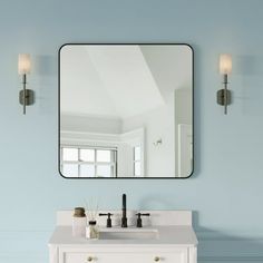 a bathroom vanity with a mirror above it and two lights on the wall behind it