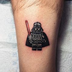 a small tattoo on the leg of a man with a lego darth vader