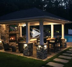 a gazebo lit up at night next to a pool