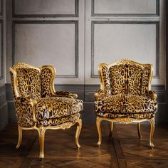 two leopard print chairs sitting next to each other on top of a hard wood floor