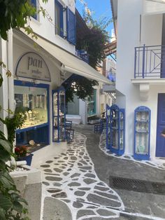 an alley way with blue and white buildings on both sides, and stone walkway leading up to the front door