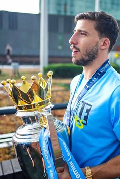 a man in blue shirt holding up a trophy and wearing a crown on top of it