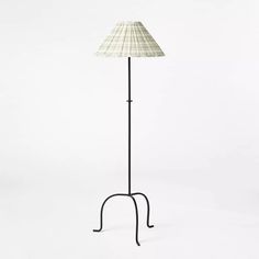 a lamp that is on top of a metal stand with a white shade over it