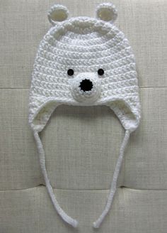 a white crocheted bear hat on top of a pillow