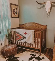 a baby crib with a cow skull mounted to the wall next to it and a rug on the floor