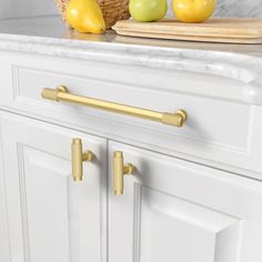 a kitchen with white cabinets and gold handles