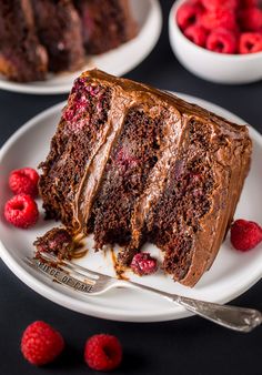 a slice of chocolate cake on a plate with raspberries