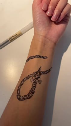 a woman's arm with a tattoo on it and a pencil in her hand