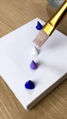 a paintbrush is being used to paint small blue and white rocks on a piece of paper