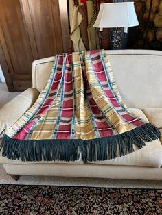 a couch with a blanket on top of it in front of a lamp and rug