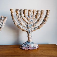 a ceramic menorah sitting on top of a wooden table next to another piece of art