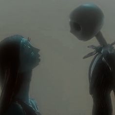 two alien like people standing next to each other