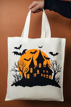 a person holding a white bag with an image of a house and bats on it