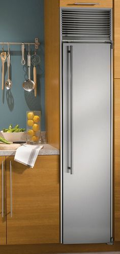 a silver refrigerator freezer sitting inside of a kitchen next to a counter top with utensils on it