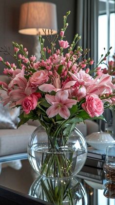 a vase filled with pink flowers sitting on top of a table next to a couch