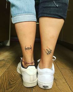 two people with matching tattoos on their legs, one is holding the other's leg