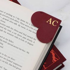 an open book sitting on top of a pile of red books with the words ac printed on it