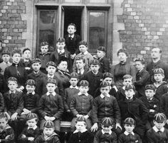 an old black and white photo of young boys in uniforms posing for a group photograph