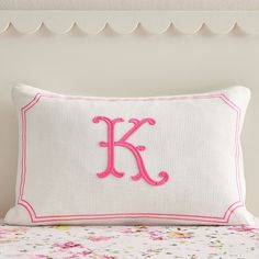 a pillow with the letter k on it sitting on top of a floral print bed