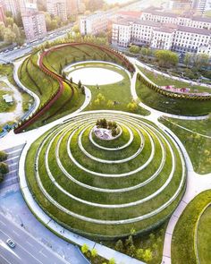 an aerial view of a circular garden in the middle of a city with lots of green grass