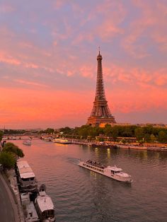 the eiffel tower towering over the city of paris at sunset with boats on the river below