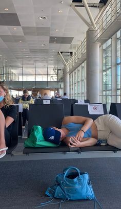 two people are laying on their backs in an airport waiting area with luggage and masks