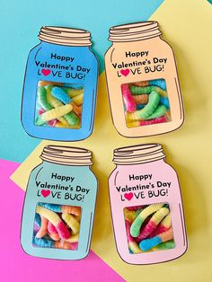 four jars filled with colorful candy sitting on top of a pink and blue tablecloth