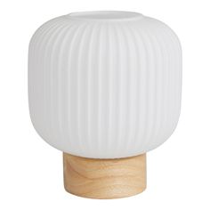 a white vase sitting on top of a wooden stand