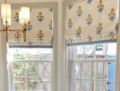 two windows with yellow and blue flowers on them in a white room next to a window sill