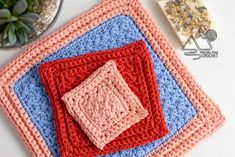 three crocheted coasters sitting on top of a table next to a potted plant