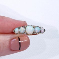 "This Victorian ring was handcrafted in England around 1900. It's a glimmery little stunner featuring five round cabochon opals patterned with 10 rose cut diamonds. The largest opal can be found at the center of the ring face, it measures 5.3 mm in diameter and 3.3 mm in depth. This piece is a size 8.25 and it weighs 4.5 grams. The ring face measures 7.5 x 22.5 and it sits 5.4 mm off the finger. It bears the gold purity mark, \"18 C\". Opals look like the universe and all her colors inside one t Opal Jewelry With Rose Cut Diamonds, Round Opal Jewelry With Rose Cut Diamonds, Victorian Style Opal Round Rings, Opal Ring With Rose Cut Diamonds, Victorian Style Round Opal Ring, Victorian Round Opal Ring Hallmarked, Victorian Hallmarked Opal Ring, Antique Hallmarked Opal Ring, Cabochon Opal Ring With Diamond