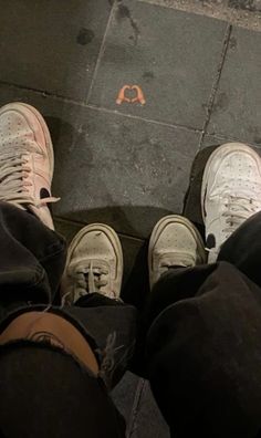 two people standing next to each other with their feet on the ground and one person wearing sneakers