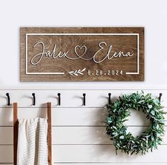 a couple's name and date on a wooden sign next to two coats rack